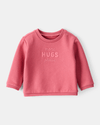 Sudadera rosa con mensaje “More Hugs Please”